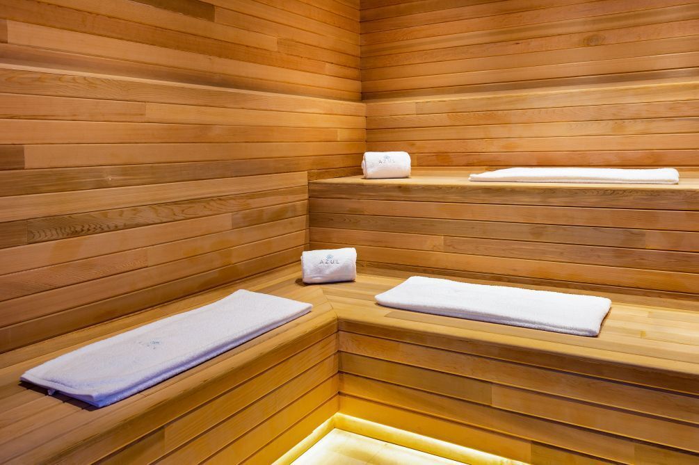 Uma sauna com bancos de madeira e toalhas em cada banco.