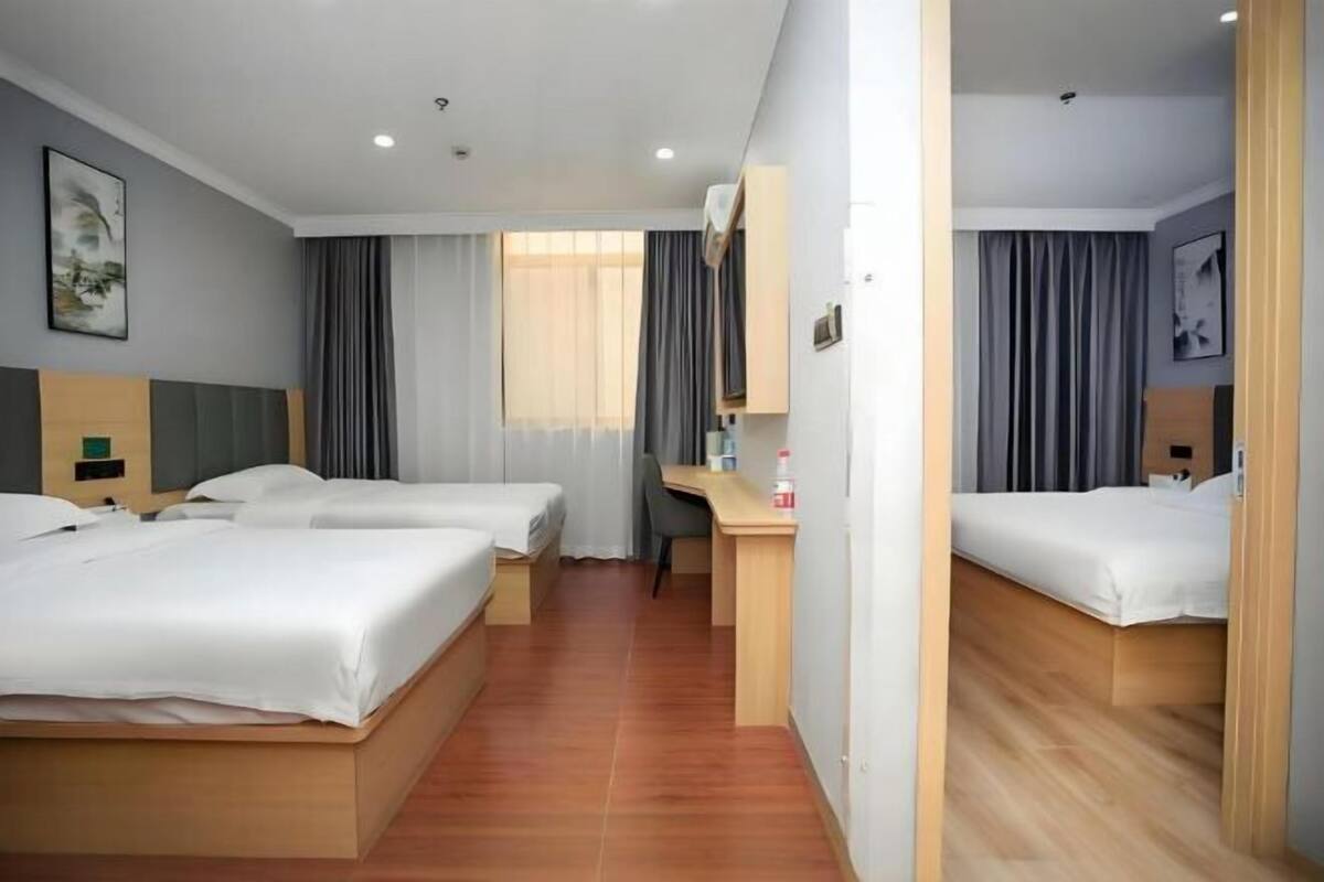 Habitación de hotel con dos camas, un escritorio y una silla.