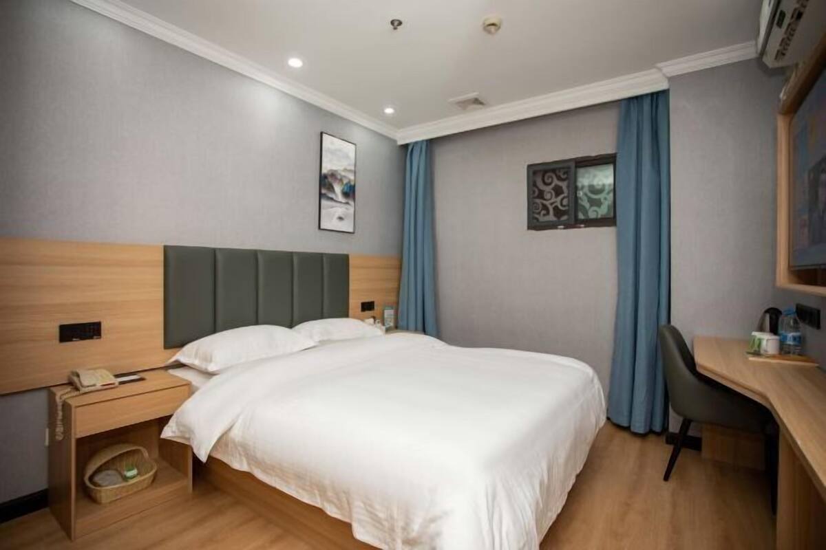 Una habitación de hotel con cama, mesita de noche, lámpara y escritorio con silla.