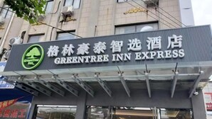 Señal de hotel con el nombre 'GreenTree Inn Express' y un logotipo que muestra un árbol y el texto 'GreenTree Inn'.