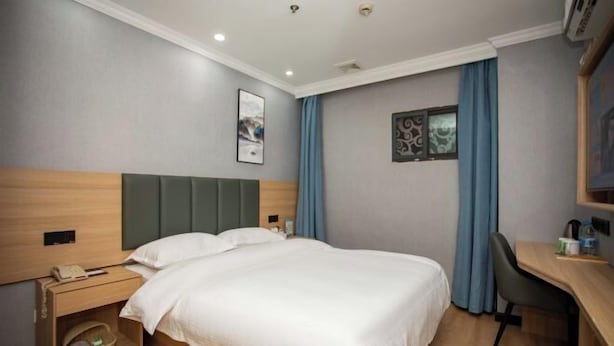 Habitación de hotel con cama, mesita de noche y escritorio con silla.