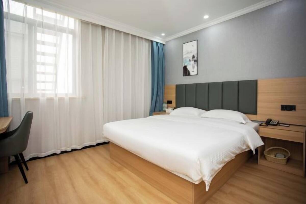 Una habitación de hotel moderna con una cama grande, un escritorio y una silla.