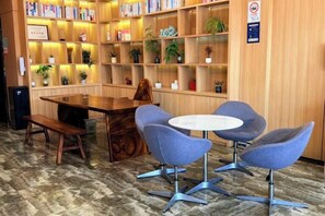 A library with bookshelves, a wooden table, and two blue chairs. - GreenTree Inn Express Hotel(Shanghai Luoqian) (Shanghai)