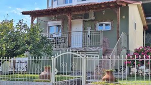 A two-story building with a balcony, a gated entrance, and potted plants.