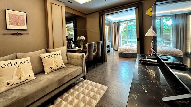 Una habitación de hotel moderna con sofá, escritorio, cama y un espejo grande.