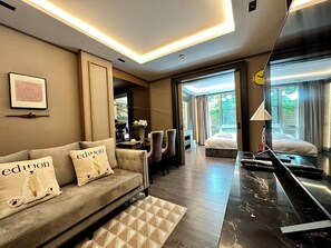 A modern hotel room with a sofa, a desk, a bed, and a large mirror.