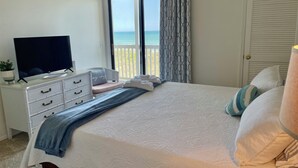 A bedroom with a bed, a TV on a dresser, a window with curtains, and a view of the sea. - Direct oceanfront 2Bed 2Bath Condo in Cherry Grove Beach with Pool (North Myrtle Beach)