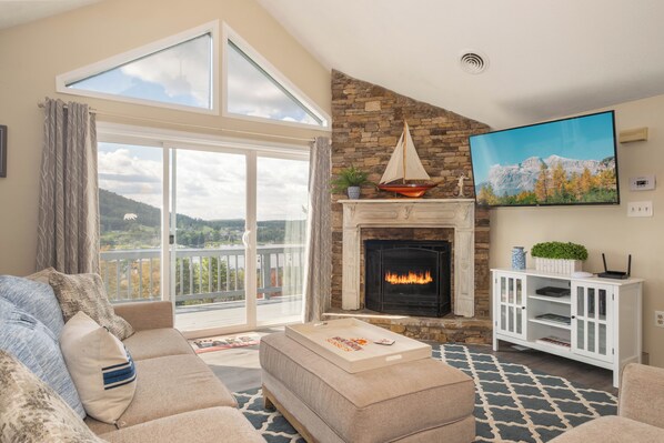 A living room with a fireplace, a large window, and a view of the outdoors.
