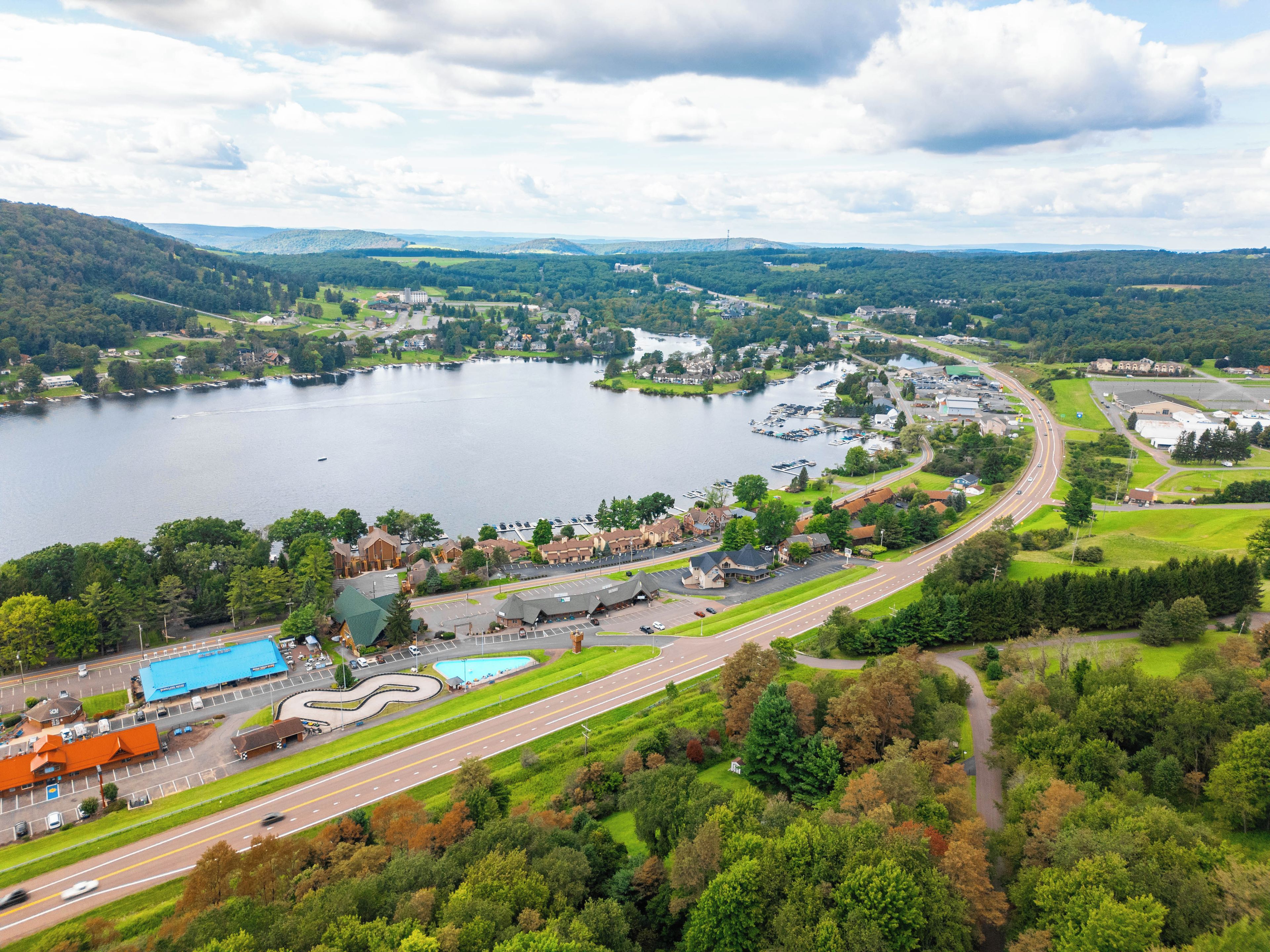 Une ville située au bord d’un lac, avec une route qui longe les rives, des bâtiments et une piscine.