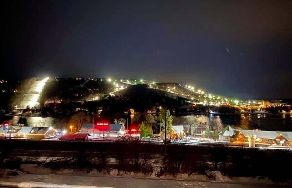 Una vista nocturna de un pueblo con edificios iluminados y un paisaje cubierto de nieve.