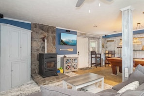 A living room with a stone wall, a fireplace, a television, and a pool table.