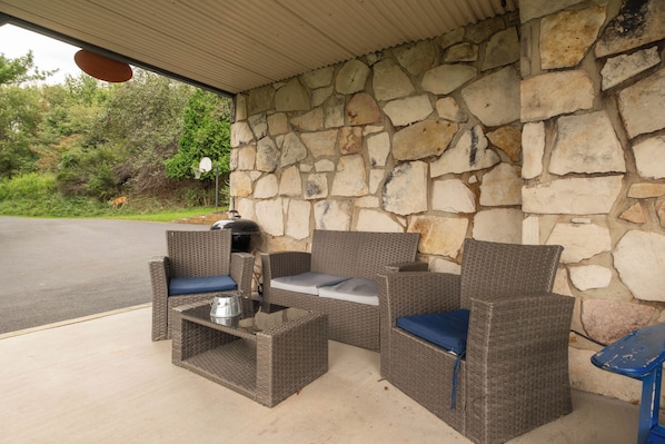 An outdoor seating area with wicker furniture and a stone wall backdrop.