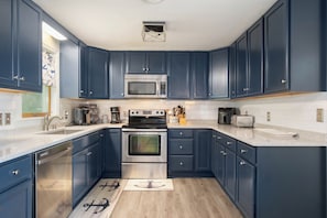 Eine moderne Küche mit dunkelblauen Schränken, Edelstahlgeräten und Holzboden.