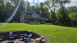 A stone house with a balcony, surrounded by a well-maintained lawn and trees.