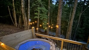A hot tub on a wooden deck surrounded by trees, with string lights. - Bear Necessities - Hot tub, Pet Friendly, Games, Fire table, Beech Mtn (Beech Mountain)