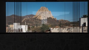 Bergblick durch ein Fenster mit vertikalen Jalousien.