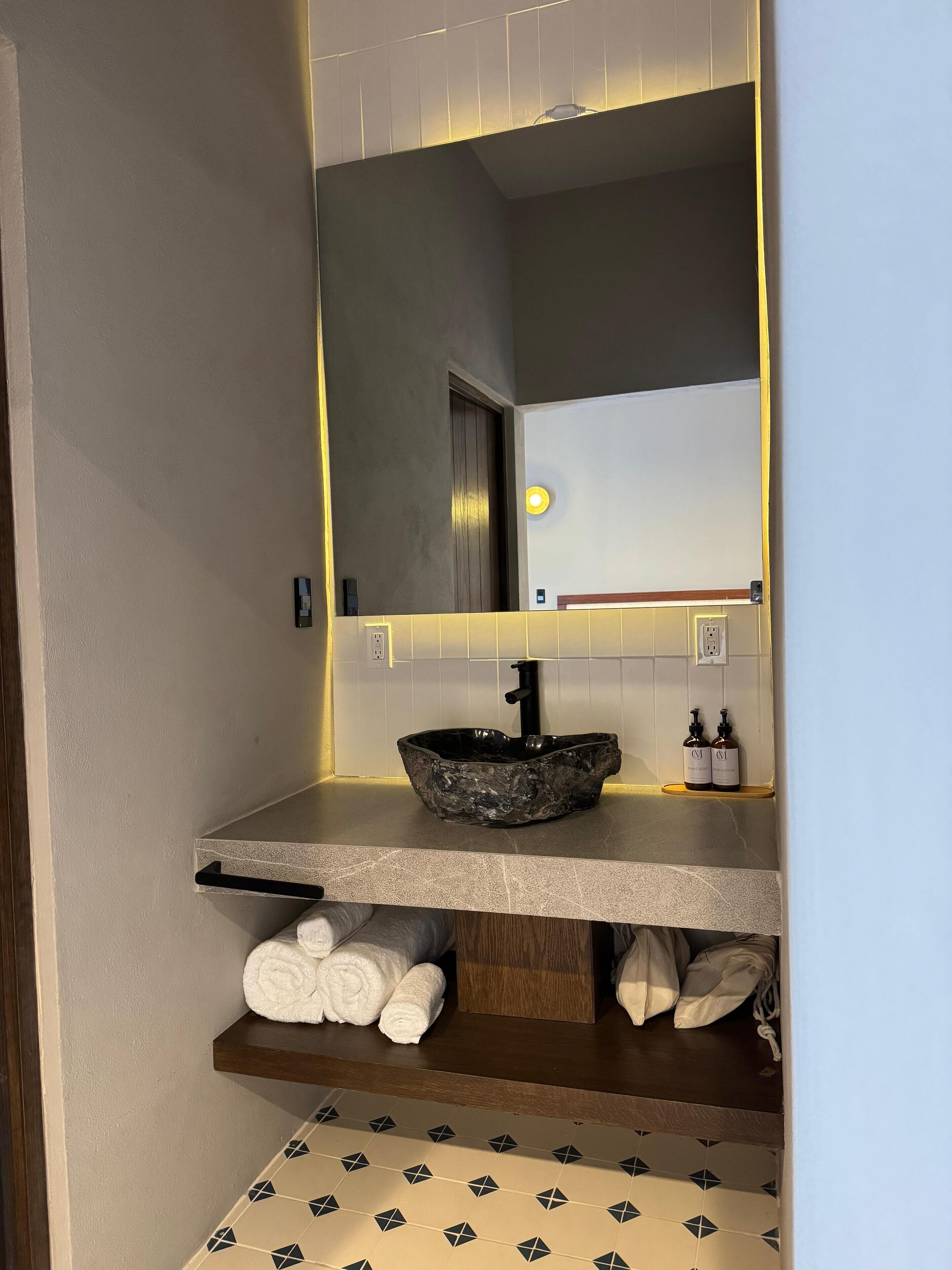 Une salle de bain avec un lavabo moderne, un miroir et un porte-serviettes.