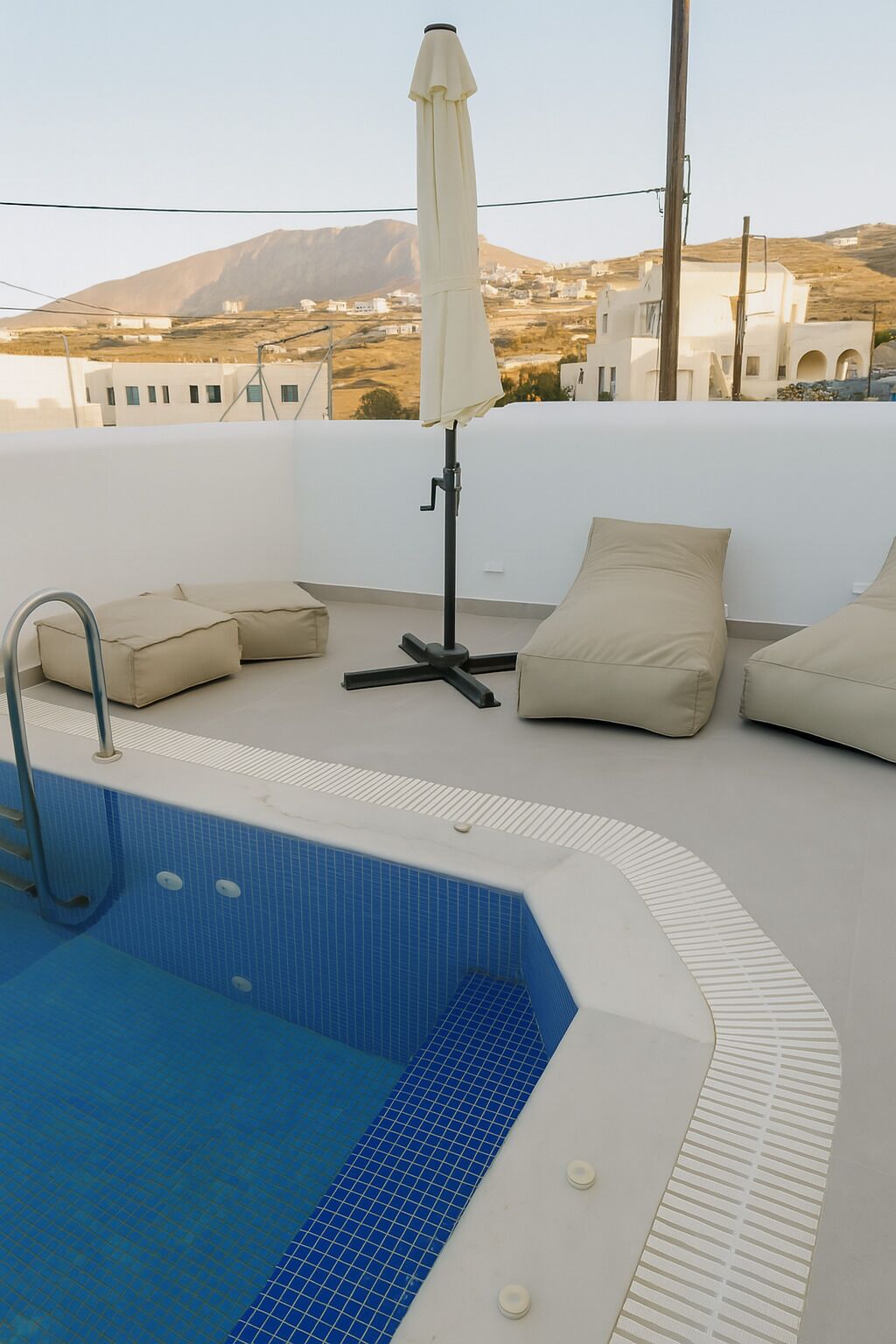 A rooftop pool area with a clear view of the surrounding landscape, including buildings and a mountain in the distance.