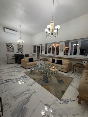 A spacious living room with a marble floor, a glass coffee table, and a chandelier. - A luxury escape, where the pool is always perfect (Juncos)