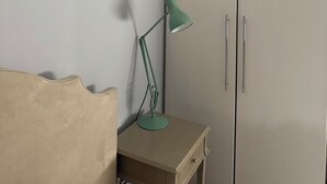 Ett hörnrum med en garderob, ett skrivbord med en lampa och en stol.