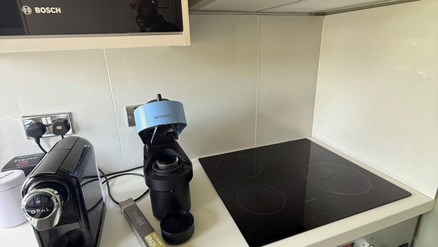 Ett kök med en Bosch-mikrovågsugn, en Nespresso-kaffemaskin och en svart induktionshäll.