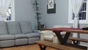 Una sala de estar con un sofá gris, un banco de madera y una planta en maceta.