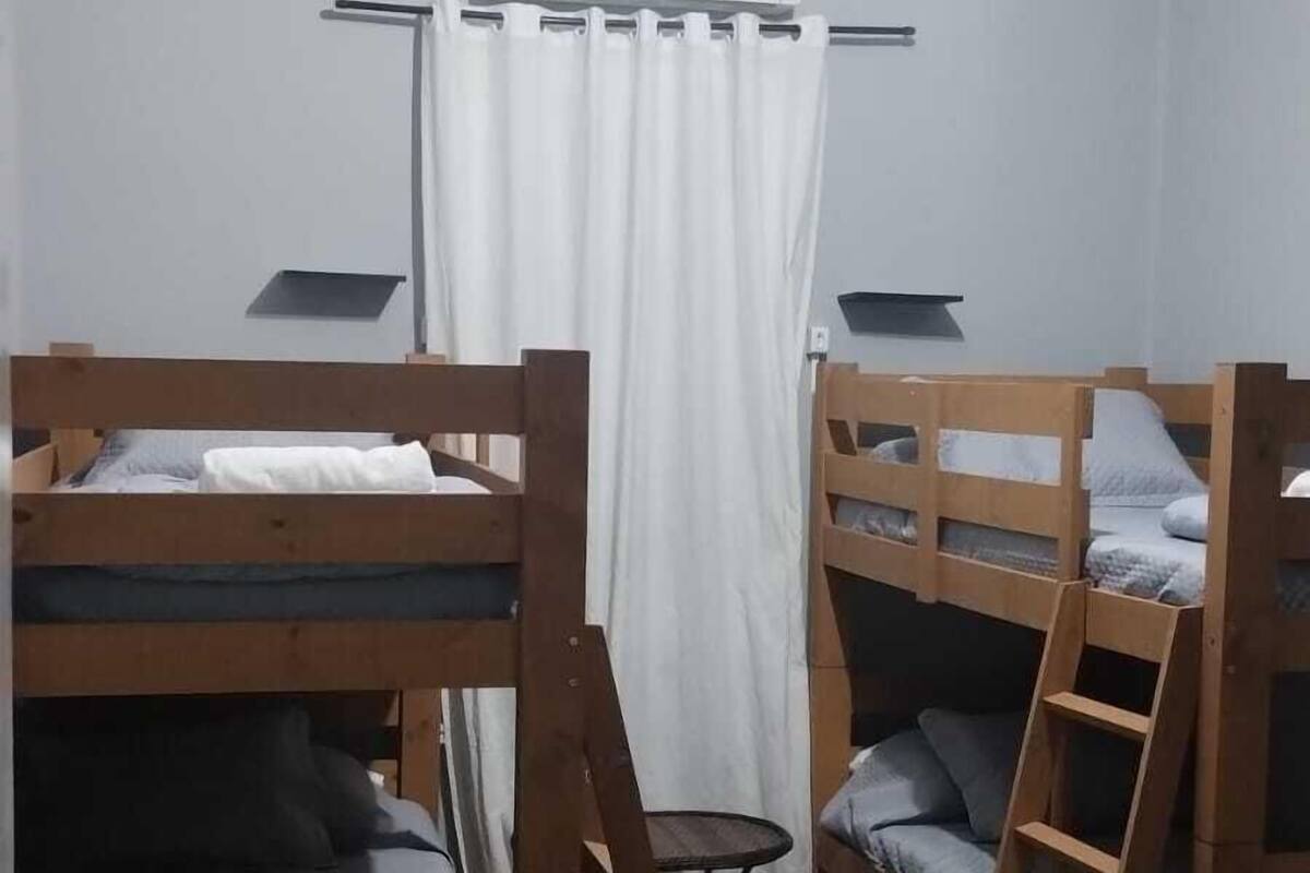 Une chambre de dortoir avec des lits superposés, une petite table et un appareil de climatisation.