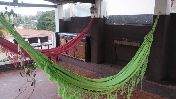 Una hamaca en un balcón con una parrilla y una pequeña mesa.