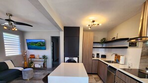 Una cocina moderna con una isla central, electrodomésticos integrados y un área de comedor con sofá y mesa de centro.