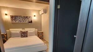 Un dormitorio moderno con una cama grande, aire acondicionado de pared y un adorno decorativo en la pared.