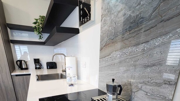 Una cocina moderna con una placa de inducción negra, una cafetera y un hervidor.
