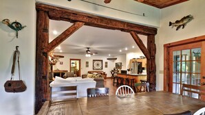 A rustic interior with a wooden dining table, a sofa, and a kitchen area.