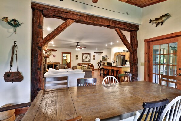 A rustic interior with a wooden dining table, a sofa, and a kitchen area.