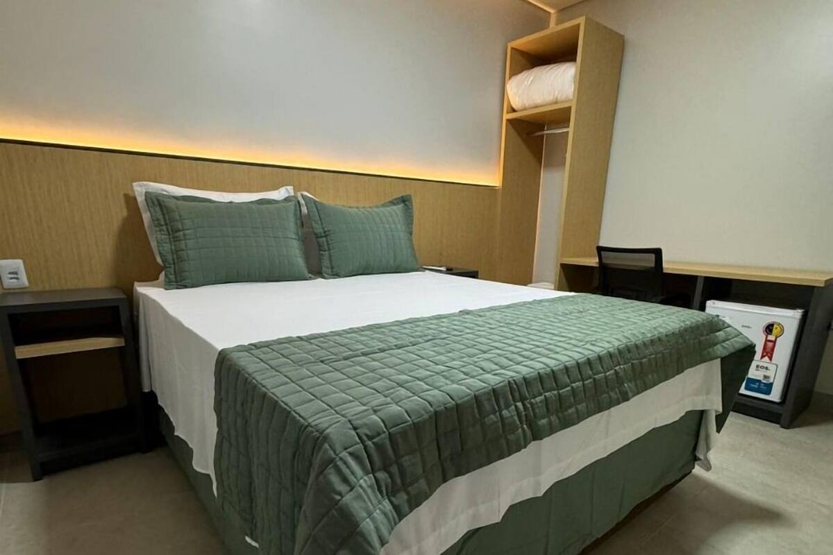 A neatly arranged hotel room with a bed, bedside tables, and a built-in shelf.