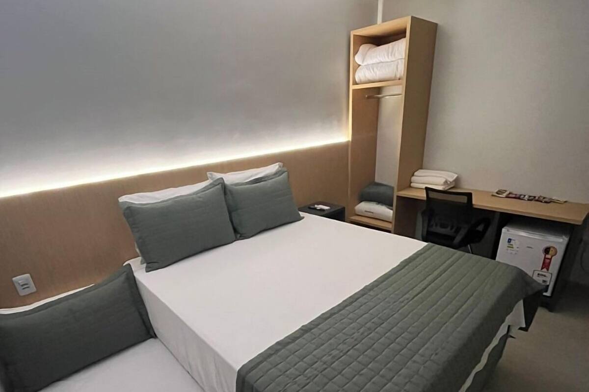 A hotel room with two single beds, a desk, a chair, and a wardrobe.
