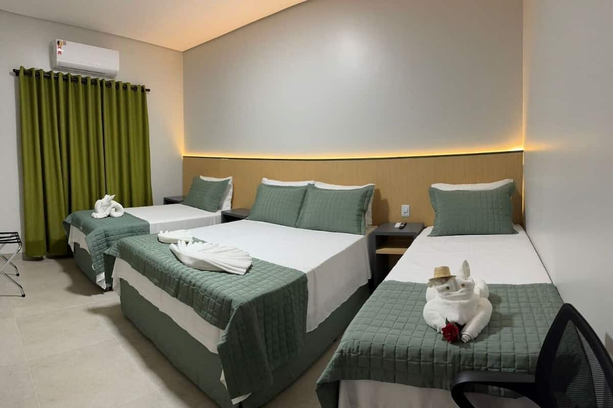 A hotel room with two beds, a desk, and a chair.