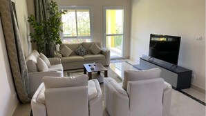 A modern living room with a sofa set, a coffee table, and a flat-screen TV. - Upscale 2 bedrooms 2B Swimming Pool in Dream Land (Giza Governorate)