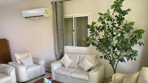 A living room with a beige sofa, two armchairs, a coffee table, and a potted plant. - Upscale 2 bedrooms 2B Swimming Pool in Dream Land (Giza Governorate)