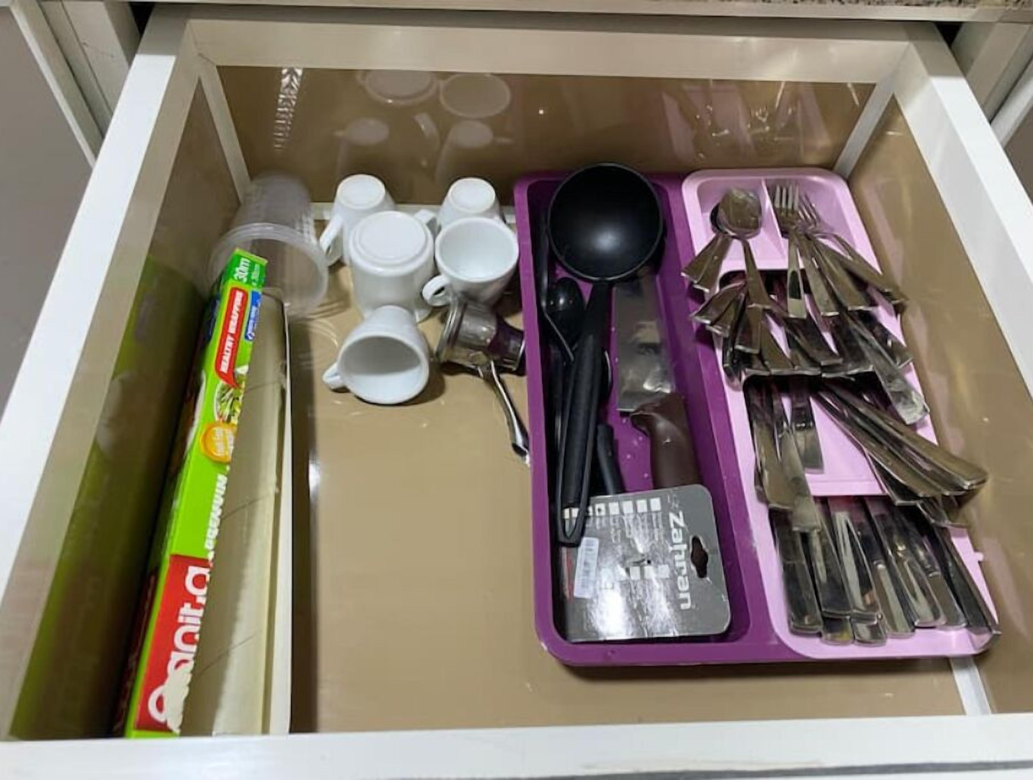 A drawer with a box of 'Cocacola' and various kitchen utensils including cups, spoons, and a ladle.