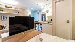 Quarto de hotel com cama, televisão, cozinha compacta e banheiro.