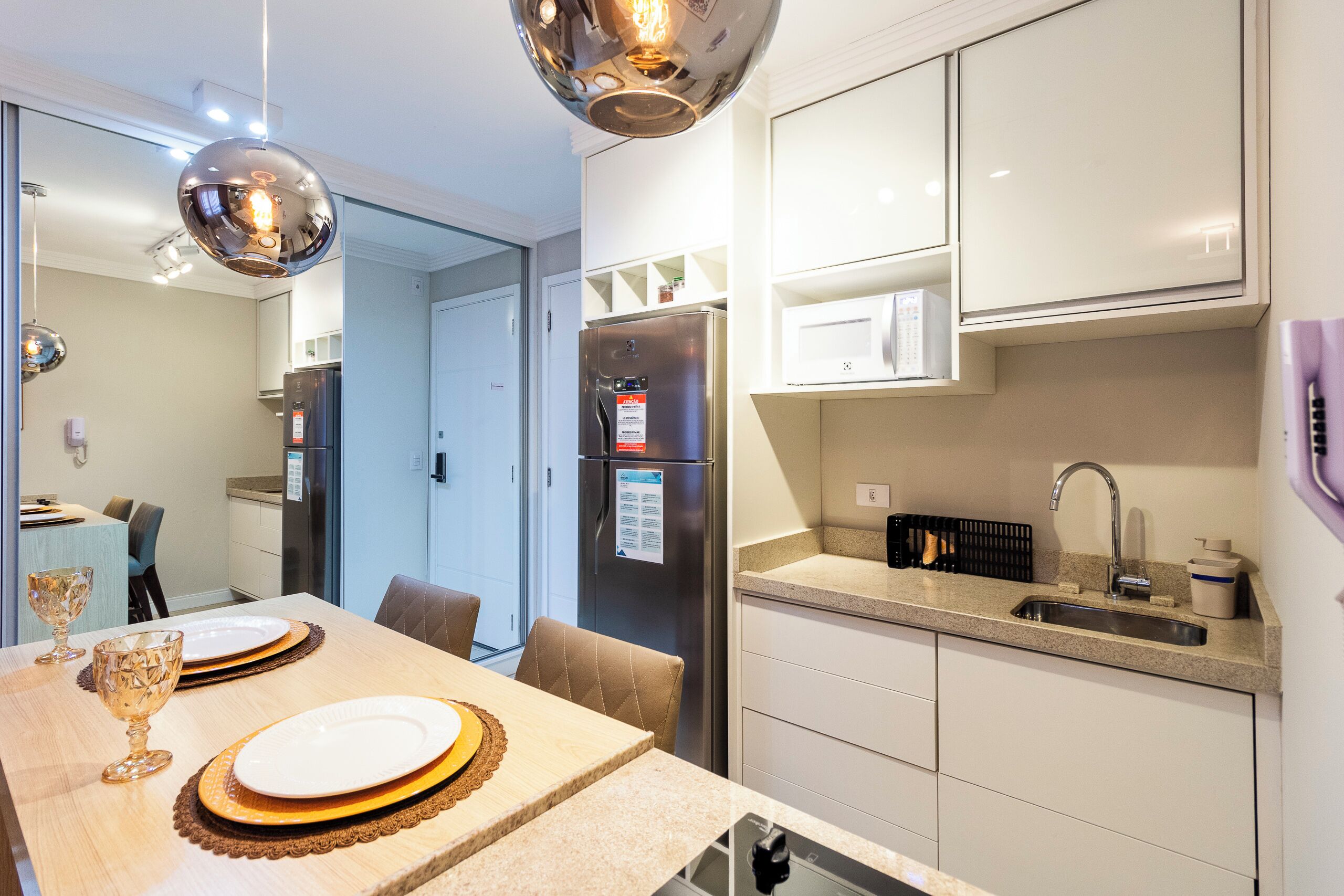 A modern kitchen with white cabinets, a stainless steel refrigerator, and a granite countertop.