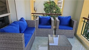 A balcony with wicker furniture and blue cushions. - Elegant 2 bedrooms 2B swimming pool in Dream Land (Giza Governorate)