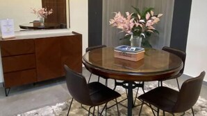 A modern dining area with a round table, four chairs, a vase of flowers, and a book on the table. - Elegant 2 bedrooms 2B swimming pool in Dream Land (Giza Governorate)