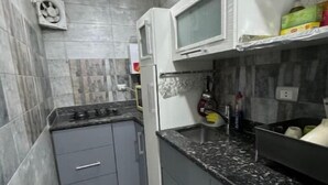A compact kitchen with grey cabinets, a black countertop, and a microwave.