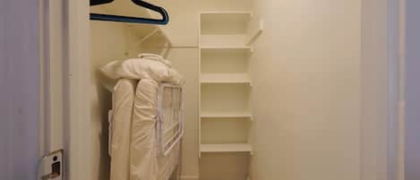 A narrow hallway with a white metal bunk bed and a white shelving unit.