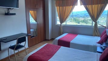 Una habitación de hotel con dos camas, un escritorio, una silla y un televisor.