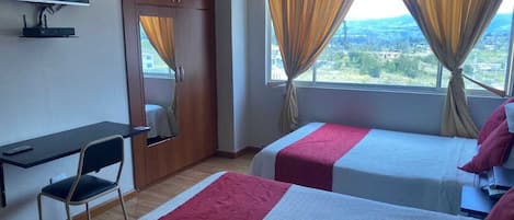 Una habitación de hotel con dos camas, un escritorio, una silla y un televisor.