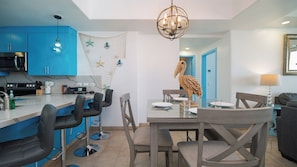 Eine moderne Küche mit blauen Schränken, ein Essbereich mit einer Holz-Pelikan-Dekoration und eine Chandelier.