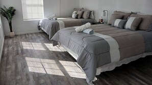 A bedroom with two beds, a potted plant, and a window with blinds. - McAllen Home Pecan - Bicentennial (McAllen)