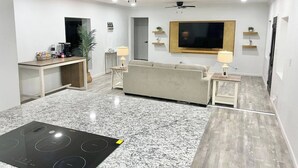 A modern living room with a kitchen area, including a stove, a sofa, and a TV. - McAllen Home Pecan - Bicentennial (McAllen)